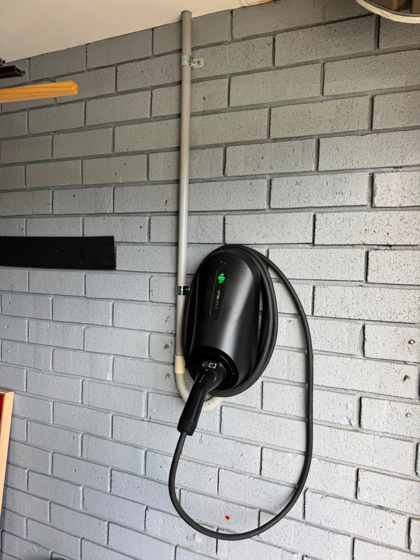 myenergi Zappi GLO charger installed on a painted brick garage wall by Candela Electrical